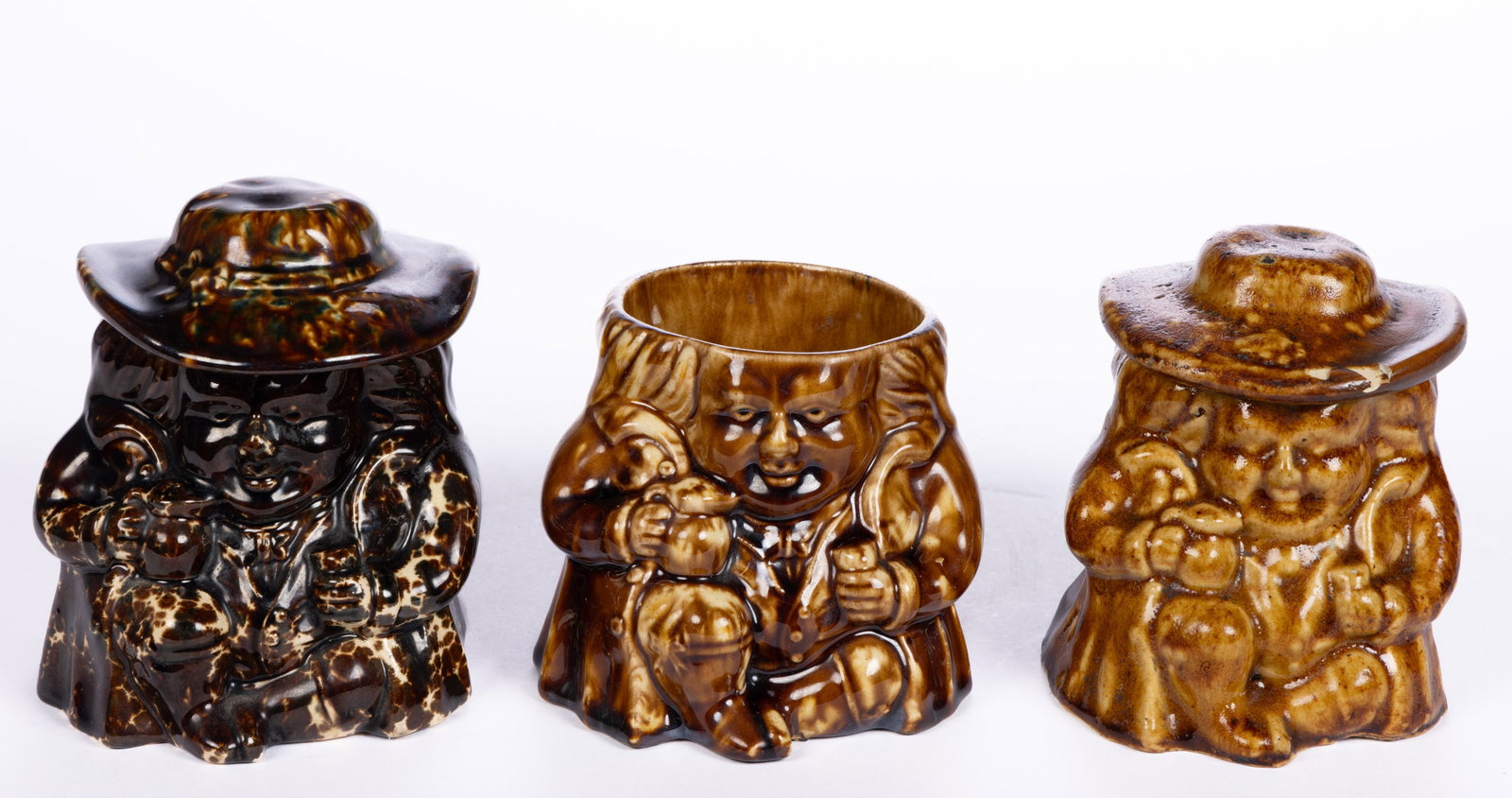 AMERICAN BENNINGTON ROCKINGHAM-GLAZE POTTERY TOBY SNUFF JARS, LOT OF THREE: AMERICAN BENNINGTON ROCKINGHAM-GLAZE POTTERY TOBY SNUFF JARS, LOT OF THREE, mottled brown glazes, each featuring a sitting portly man holding a jug and glass, comprising two examples having remov