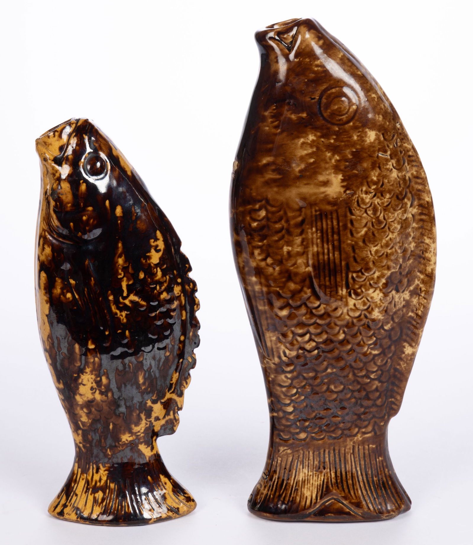 AMERICAN ROCKINGHAM-GLAZED FISH BOTTLES / FLASKS, LOT OF TWO: AMERICAN ROCKINGHAM-GLAZED FISH BOTTLES / FLASKS, LOT OF TWO, mottled brown glaze, each having detailed design including molded scales and fins. Second half 19th century. 8 7/8" to 11" LOA.&