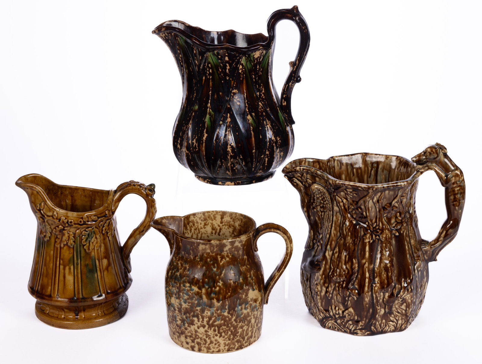 AMERICAN FLINT ENAMEL ROCKINGHAM-GLAZED PITCHERS, LOT OF FOUR: AMERICAN FLINT ENAMEL ROCKINGHAM-GLAZED PITCHERS, LOT OF FOUR, comprising one example with diamond pattern having mottled dark brown and green glazes, and three examples having mottled brown and blue 