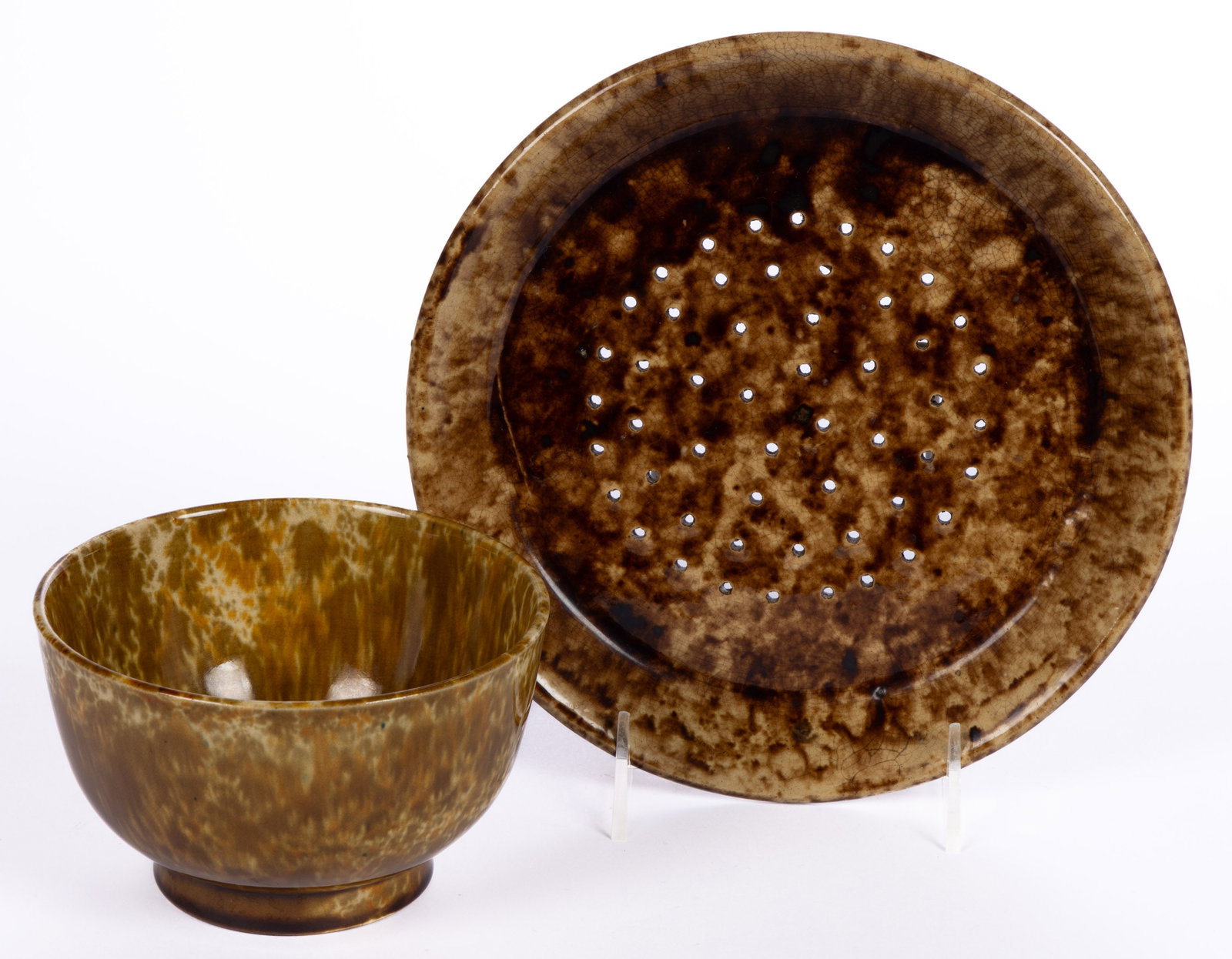 AMERICAN ROCKINGHAM-GLAZED POTTERY COLANDERS, LOT OF TWO: AMERICAN ROCKINGHAM-GLAZED POTTERY COLANDERS, LOT OF TWO, each with mottled brown glazes, comprising a 5 1/2" D deep-form bowl example with additional orange flint enamel decorations and one plat