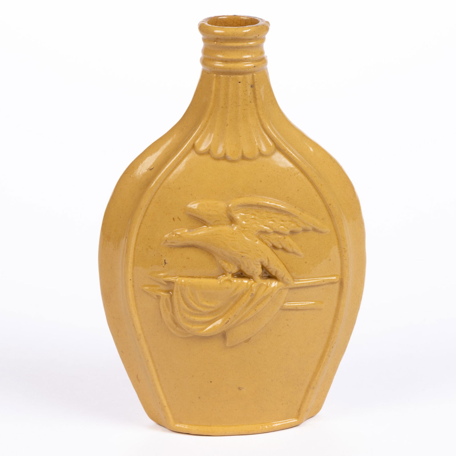 AMERICAN HISTORICAL YELLOWWARE BOTTLE / FLASK: AMERICAN HISTORICAL YELLOWWARE BOTTLE / FLASK, embossed American eagle perched to two furled flags on one side and reverse with morning glory pattern. Unmarked. Circa 1875. 7 1/8" HOA. 