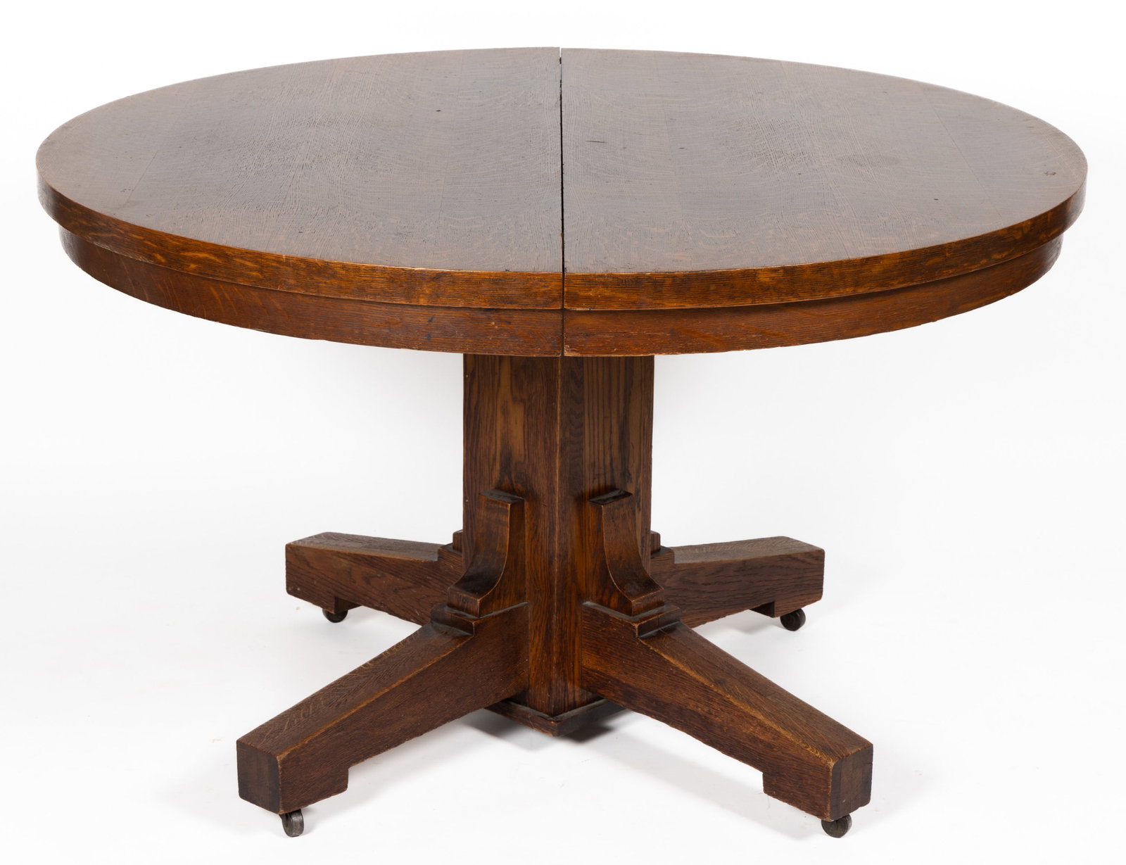AMERICAN ARTS & CRAFTS / MISSION OAK DINING TABLE: AMERICAN ARTS & CRAFTS / MISSION OAK DINING TABLE, featuring a circular top with three extension boards, raised on a pedestal base, legs with likely original casters, no markings located. Retains 