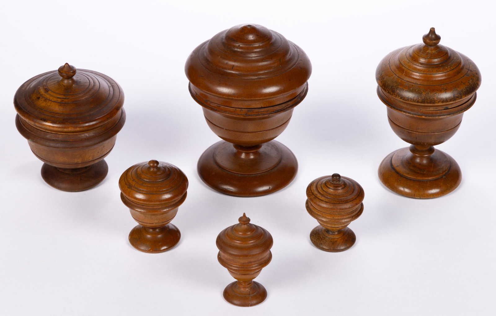 AMERICAN TURNED PEASEWARE / TREEN CONTAINERS, LOT OF SIX: AMERICAN TURNED PEASEWARE / TREEN CONTAINERS, LOT OF SIX, storage jar example, each with likely original covers. Each retains an old surface with warm color. 19th century. 2" to 5 1/2" H. Pr