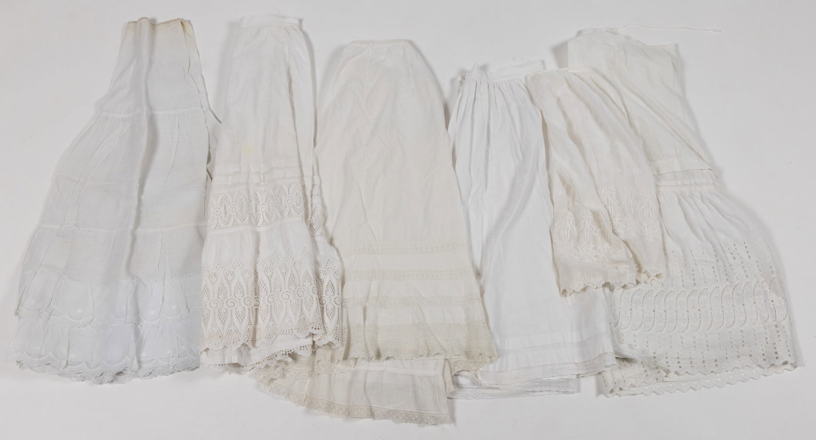 VICTORIAN / EDWARDIAN WHITE PETTICOATS / SKIRTS, LOT OF 11: VICTORIAN / EDWARDIAN WHITE PETTICOATS / SKIRTS, LOT OF 11, including lace, eyelet, and embroidered accents. Late 19th/early 20th century. One skirt with interior lining and fine lace trim 41 1/2"