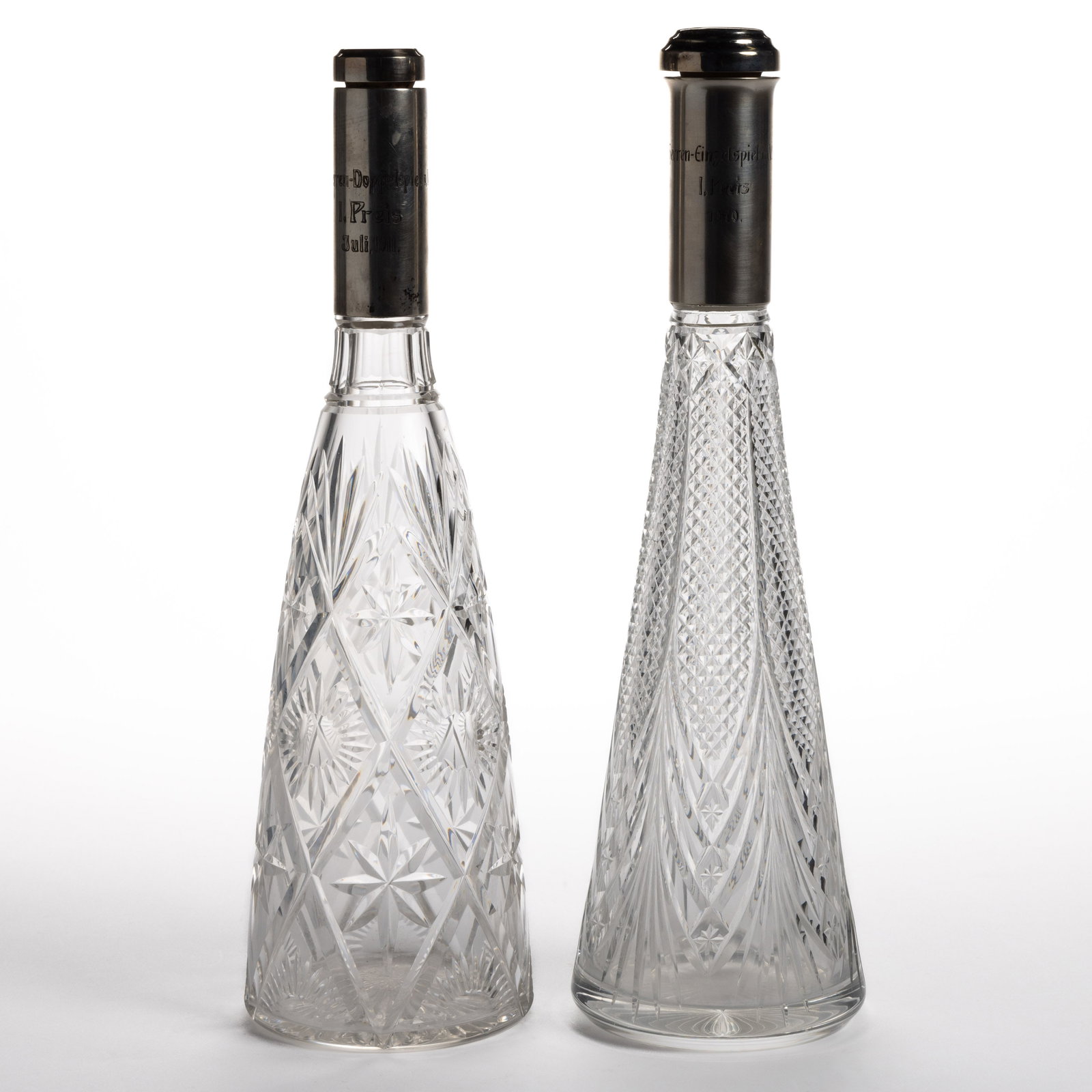 GERMAN TENNIS TROPHY / PRESENTATION 0.800 SILVER-COLLARED AND CUT GLASS DECANTERS, LOT OF TWO: GERMAN TENNIS TROPHY / PRESENTATION 0.800 SILVER-COLLARED AND CUT GLASS DECANTERS, LOT OF TWO, each having a tapered-form colorless cut-glass bottle with applied 0.800 silver collar having presentatio