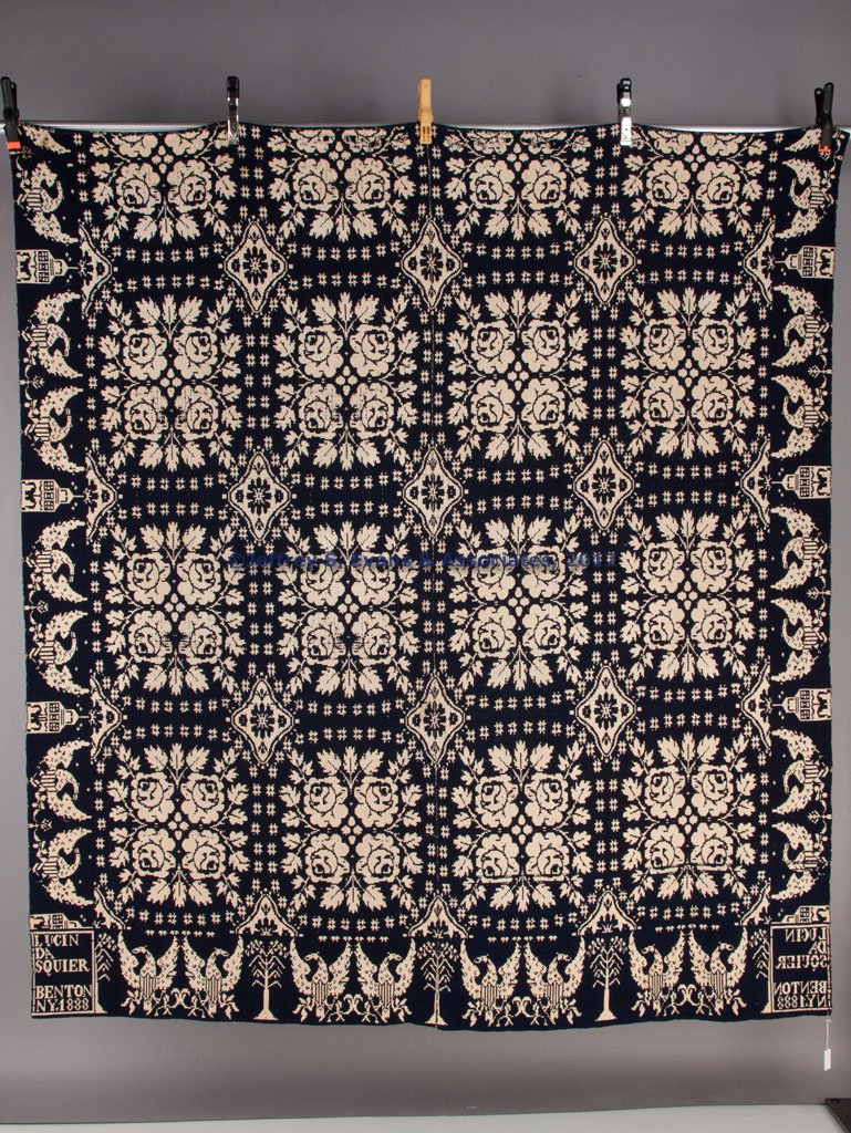 NEW YORK JACQUARD COVERLET: NEW YORK JACQUARD COVERLET, dark blue and white, comprising two joined panels, rose medallion and star central design, American eagle, building and tree border with corner blocks inscribed "LUCINDA SQ