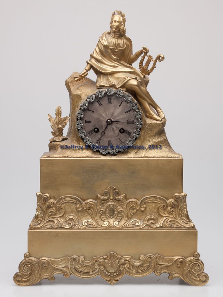 FRENCH DORE BRONZE FIGURAL CLOCK CASE: FRENCH DORE BRONZE FIGURAL CLOCK CASE, depicting a music teacher with lyre seated on a rock ledge. Fitted with a non-original movement. 19th century. 15" H.