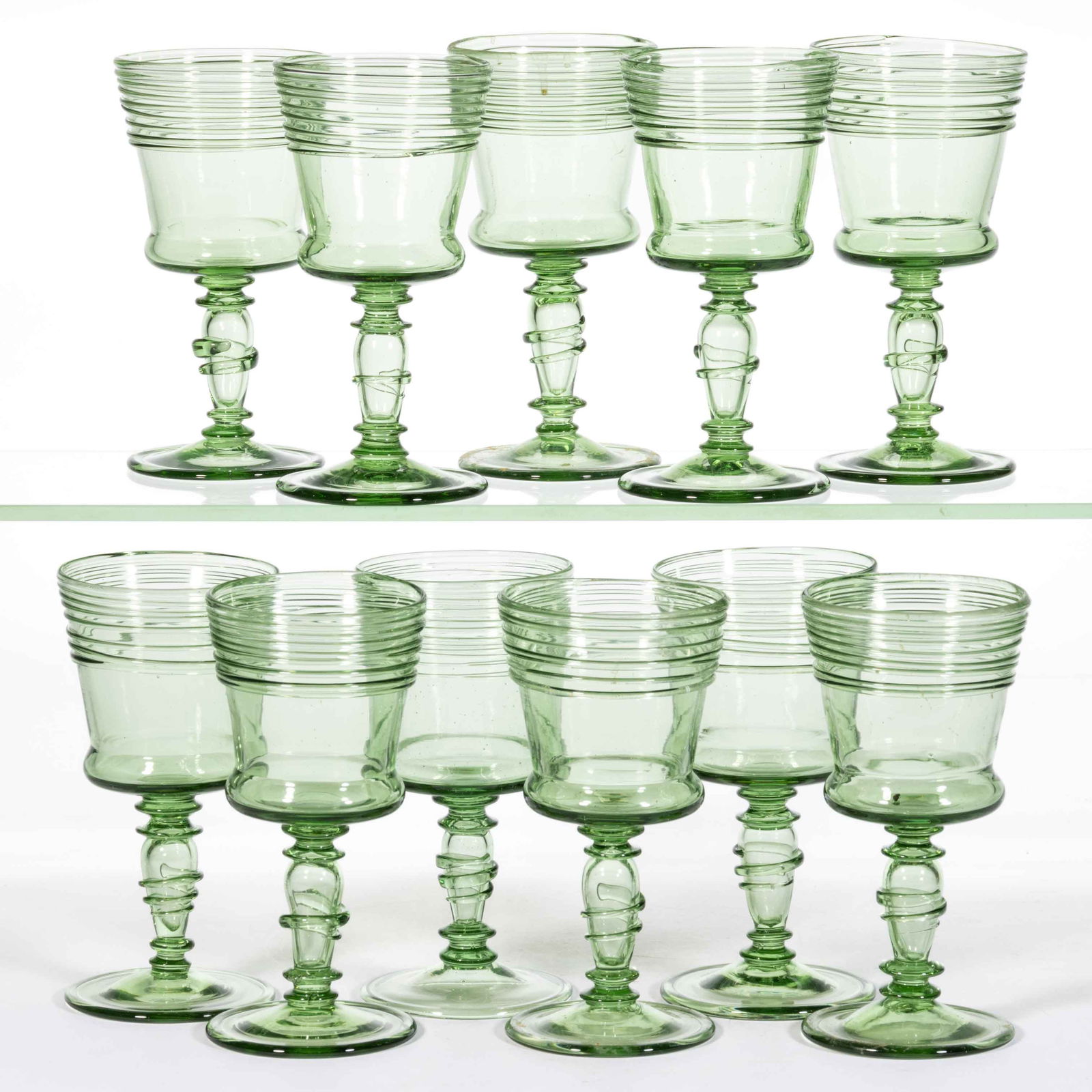 STEUBEN ATTRIBUTED NO. 6333 ART GLASS WINES, LOT OF 11: STEUBEN ATTRIBUTED NO. 6333 ART GLASS WINES, LOT OF 11, Spanish Green, each having Spanish Green threading with hollow stems with applied decoration. Steuben Glass Works. Circa 1925. 5 7/8" H. Provena
