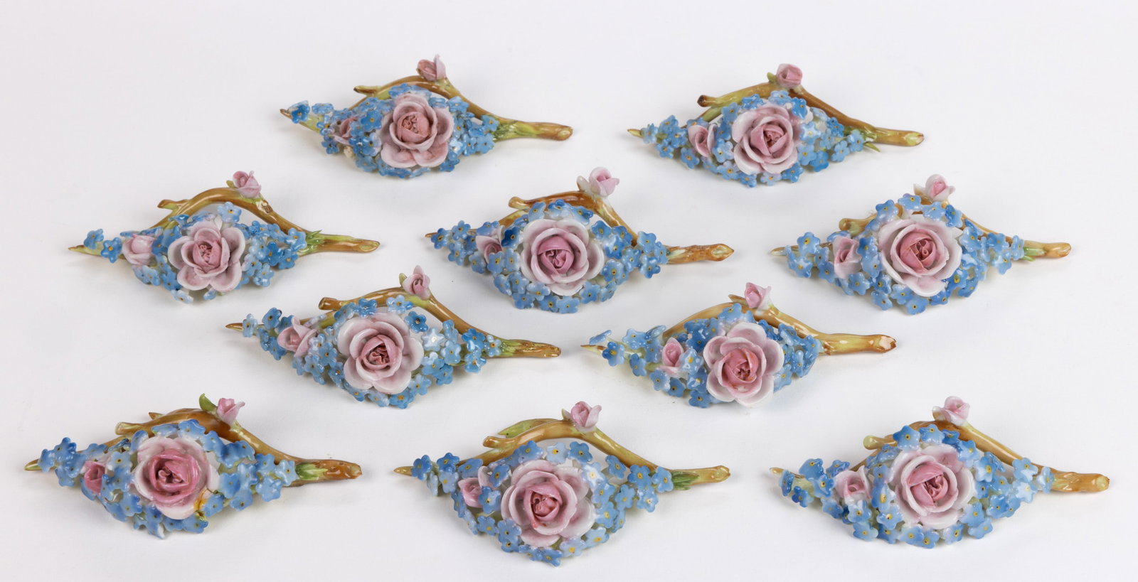 GERMAN PORCELAIN HAND-PAINTED FLORAL PLACE CARD HOLDERS, LOT OF TEN: GERMAN PORCELAIN HAND-PAINTED FLORAL PLACE CARD HOLDERS, LOT OF TEN, each featuring delicate applied blue flowers surrounding a pink rose on a cut stem with polychrome decorations. Each havi