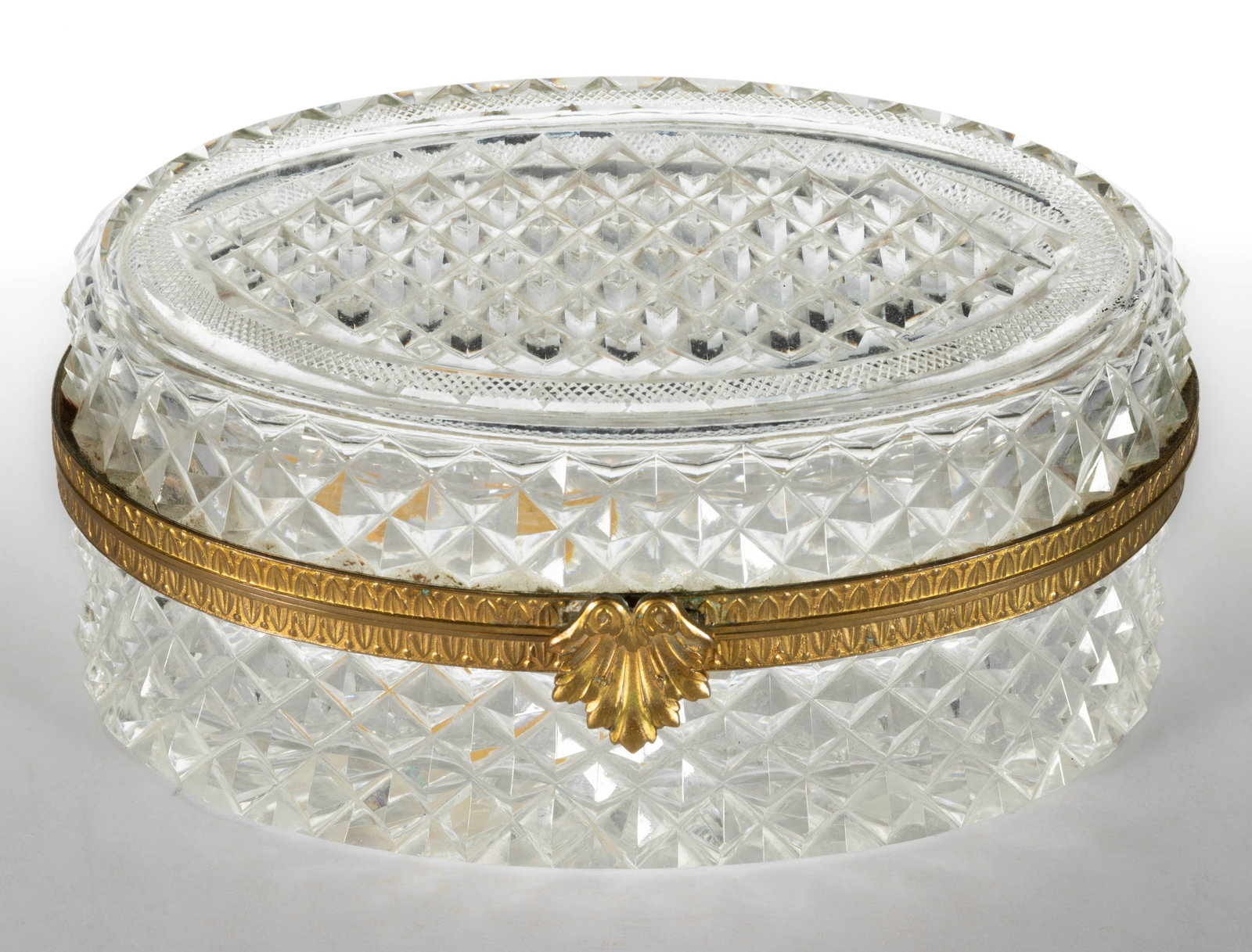 FRENCH CUT GLASS JEWEL BOX: FRENCH CUT GLASS JEWEL BOX, oval form with hinged lid, cut with an allover diamond-point design, star-cut base, gilt-brass mounts and clasp. Second half 19th/early 20th century. 3 1/2" H, 7"