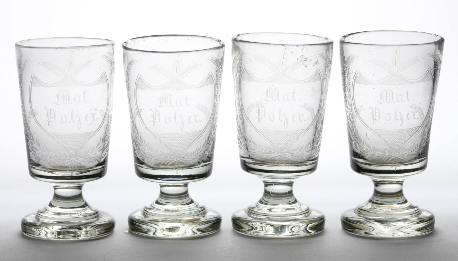 BLOWN ENGRAVED GLASS FOOTED TUMBLERS, SET OF FOUR: BLOWN ENGRAVED GLASS FOOTED TUMBLERS, SET OF FOUR, heavy colorless glass, two-stepped thick foot with plain stem and cylindrical bodies with slight outward taper, all engraved seemingly &quo