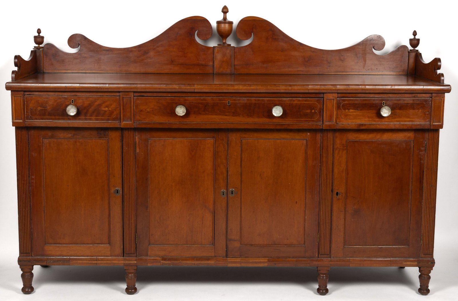 SOUTHERN CLASSICAL INLAID CHERRY SIDEBOARD: SOUTHERN CLASSICAL INLAID CHERRY SIDEBOARD, of generous proportions, the long rectangular two-board top with applied edging and topped by a boldly scrolling gallery with urn-form finials, above three 