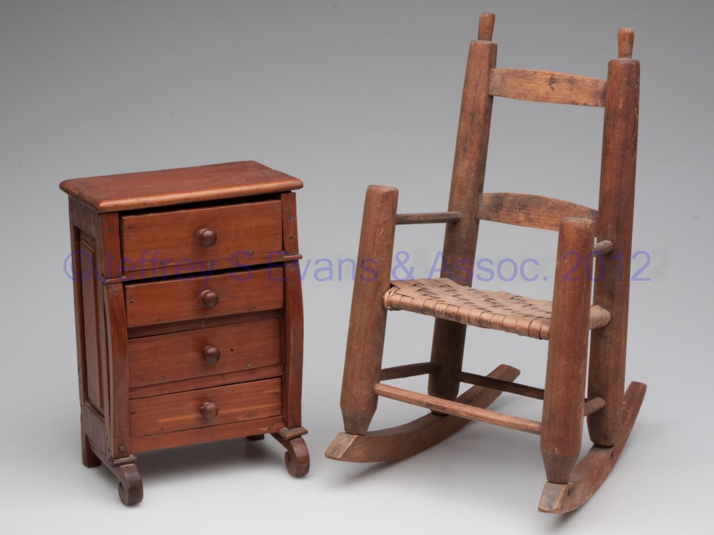 WOODEN DOLL FURNITURE, LOT OF TWO: WOODEN DOLL FURNITURE, LOT OF TWO, comprising an Empire-style chest of drawers and a split-bottom arm rocker. 19th century. 9" and 13" H. Provenance: Collection of Leah and the late Bill Pollard, Purc