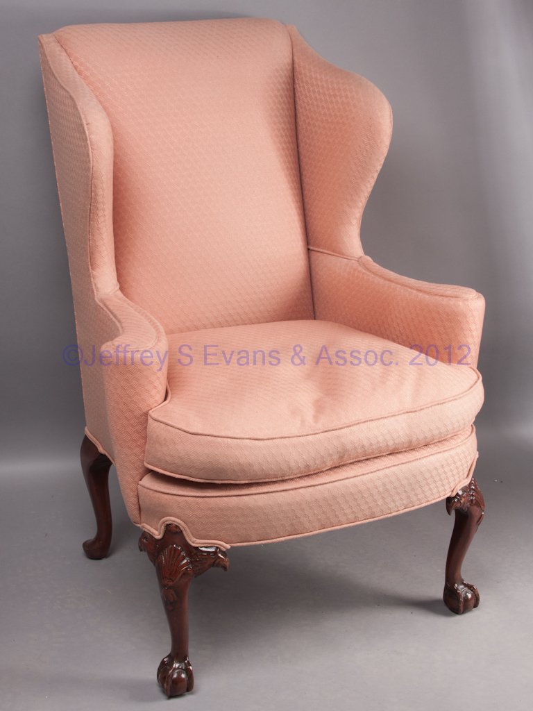 GEORGIAN-STYLE WING-BACK EASY CHAIR: GEORGIAN-STYLE WING-BACK EASY CHAIR, front legs carved with eagle heads and shells on knees, and claw-and-ball feet, down-filled cushion. Late 19th/early 20th century. 45" HOA, 22" H seat. Provenance: