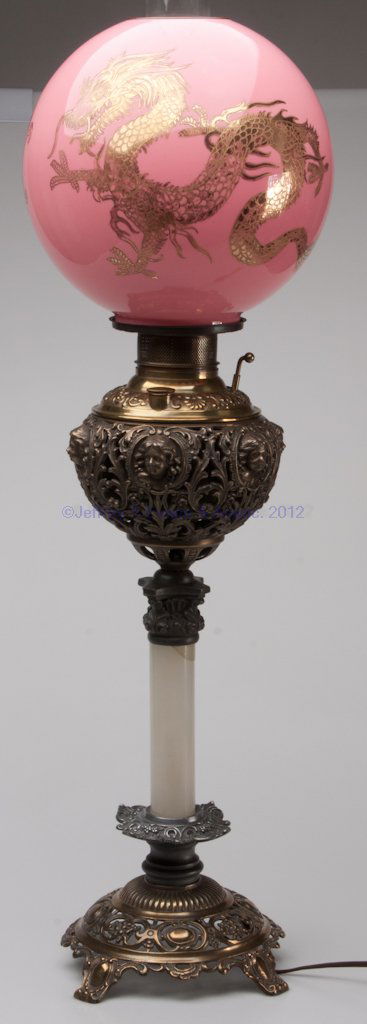 VICTORIAN BANQUET LAMP: VICTORIAN BANQUET LAMP, assorted metals and alabaster, cherub masks on font holder, cased pink ball shade with gilt dragons. Converted to electric. Fourth quarter 19th century. 20" H to collar, 9 1/2"