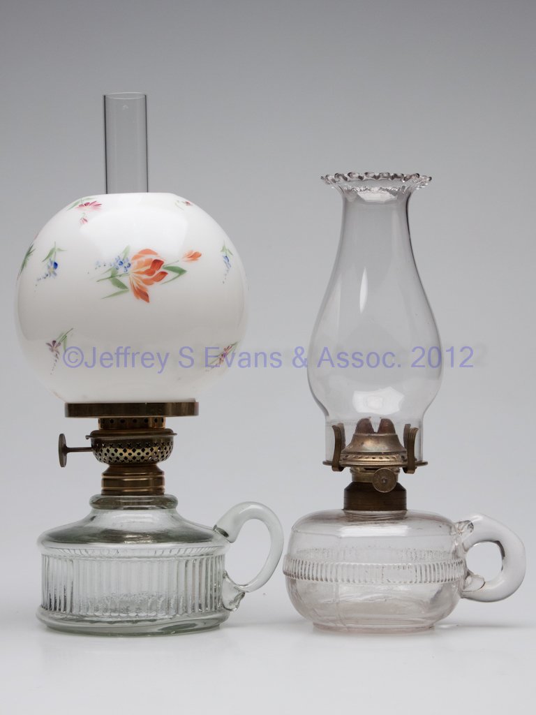 ASSORTED GLASS KEROSENE FINGER LAMPS, LOT OF TWO: ASSORTED GLASS KEROSENE FINGER LAMPS, LOT OF TWO, each with rib band pattern, one with burner and petal-top chimney, other with applied handle, burner and decorated ball shade. Second half 19th centur