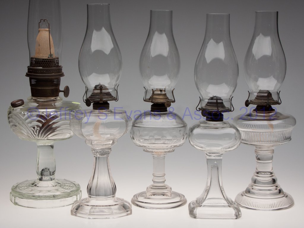 ASSORTED GLASS KEROSENE STAND LAMPS, LOT OF FIVE: ASSORTED GLASS KEROSENE STAND LAMPS, LOT OF FIVE, colorless, including Riverside Rib Band and Aladdin Model B Washington Drape, each with burner and chimney. Fourth quarter 19th/first quarter 20th cen