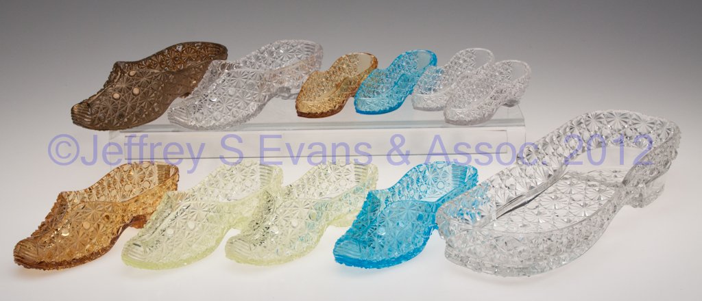 ASSORTED PRESSED GLASS FIGURAL SHOES, LOT OF 11: ASSORTED PRESSED GLASS FIGURAL SHOES, LOT OF 11, colored and colorless, each low heel and with Daisy & Button type pattern. Late 19th/early 20th century. 4 1/4" to 12" L. Provenance: From a Michigan e