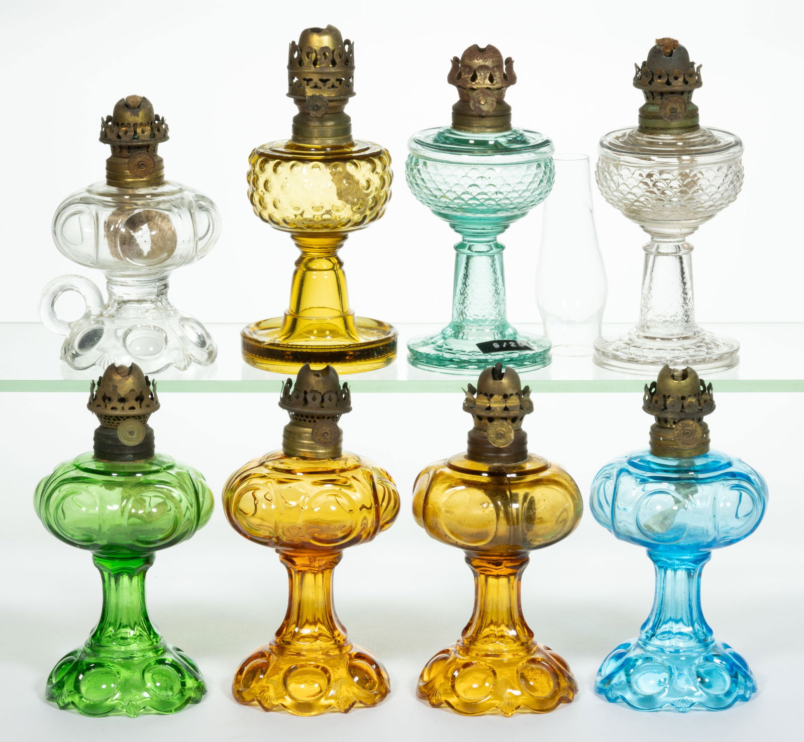 ASSORTED PATTERN MINIATURE STAND AND FOOTED FINGER LAMPS, LOT OF EIGHT: ASSORTED PATTERN MINIATURE STAND AND FOOTED FINGER LAMPS, LOT OF EIGHT, amber, blue, colorless, and green, patterns include four Daisy/Smith I, fig. 112 examples; two Fish Scale/ Smith I, fig. 11