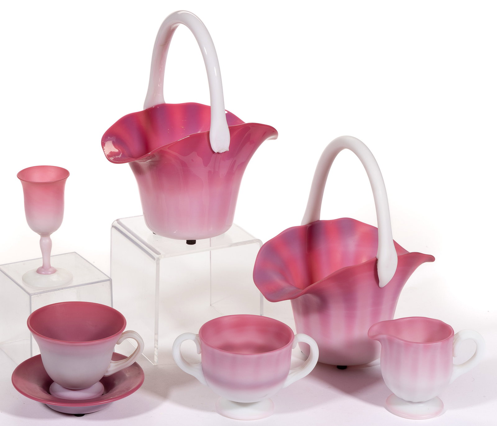 GUNDERSON PEACHBLOW GLASS ARTICLES, LOT OF SEVEN: GUNDERSON PEACHBLOW GLASS ARTICLES, LOT OF SEVEN, plush and glossy, comprising two baskets, a cream and sugar set, a wine, and a cup and saucer. Gunderson Glass Works. 1940-1960.1 1/4" to 9 7/8&q