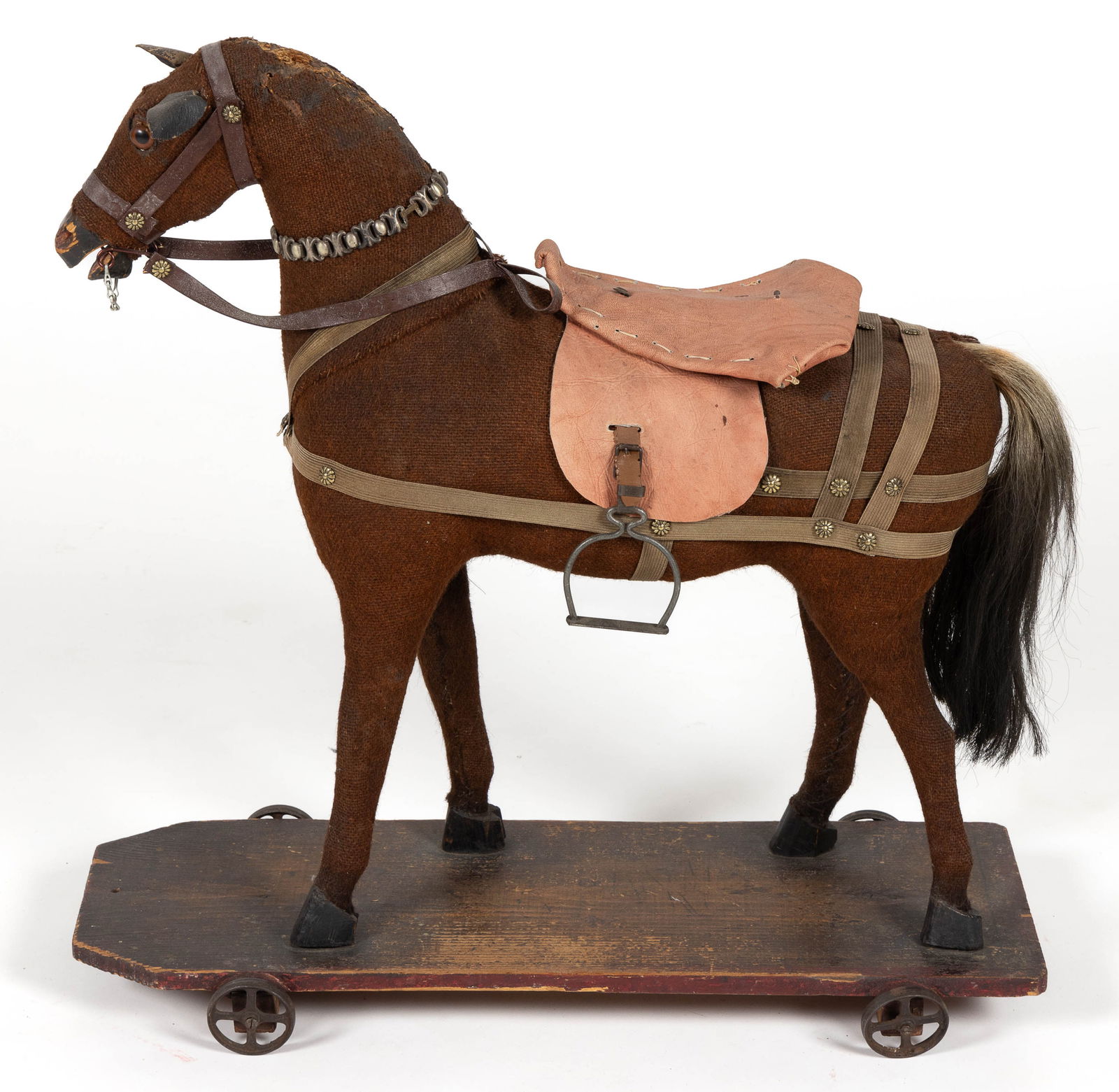 LARGE GERMAN CARVED WOOD AND STUFFED HORSE PULL-TOY: LARGE GERMAN CARVED WOOD AND STUFFED HORSE PULL-TOY, mounted on wooden base with cast-iron wheels, has a real-hair tail, body is covered in a burlap-type material, some of the tack likely original, so