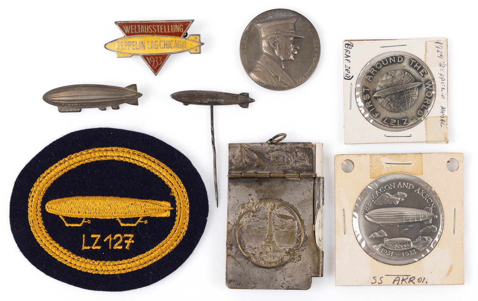 ASSORTED ZEPPELIN / DIRIGIBLE ARTICLES, LOT OF EIGHT: ASSORTED ZEPPELIN / DIRIGIBLE ARTICLES, LOT OF EIGHT, comprising a "LZ 127" patch, three pins, one reading "WELTAUSSTELLUNG / ZEPPELIN TAG CHICAGO / 1933", three medals, one of whi