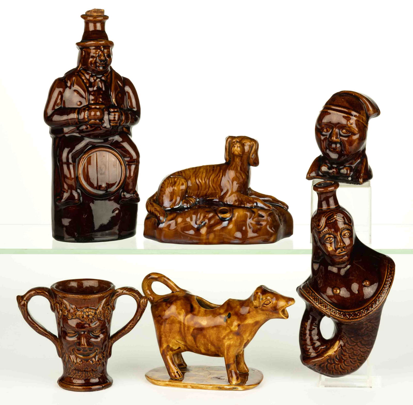AMERICAN ROCKINGHAM GLAZE POTTERY FIGURAL ARTICLES, LOT OF SIX: AMERICAN ROCKINGHAM GLAZE POTTERY FIGURAL ARTICLES, LOT OF SIX, comprising two bottles/flasks including a mermaid and a Toby Barrel example with incised "2", a double-handled Bacch