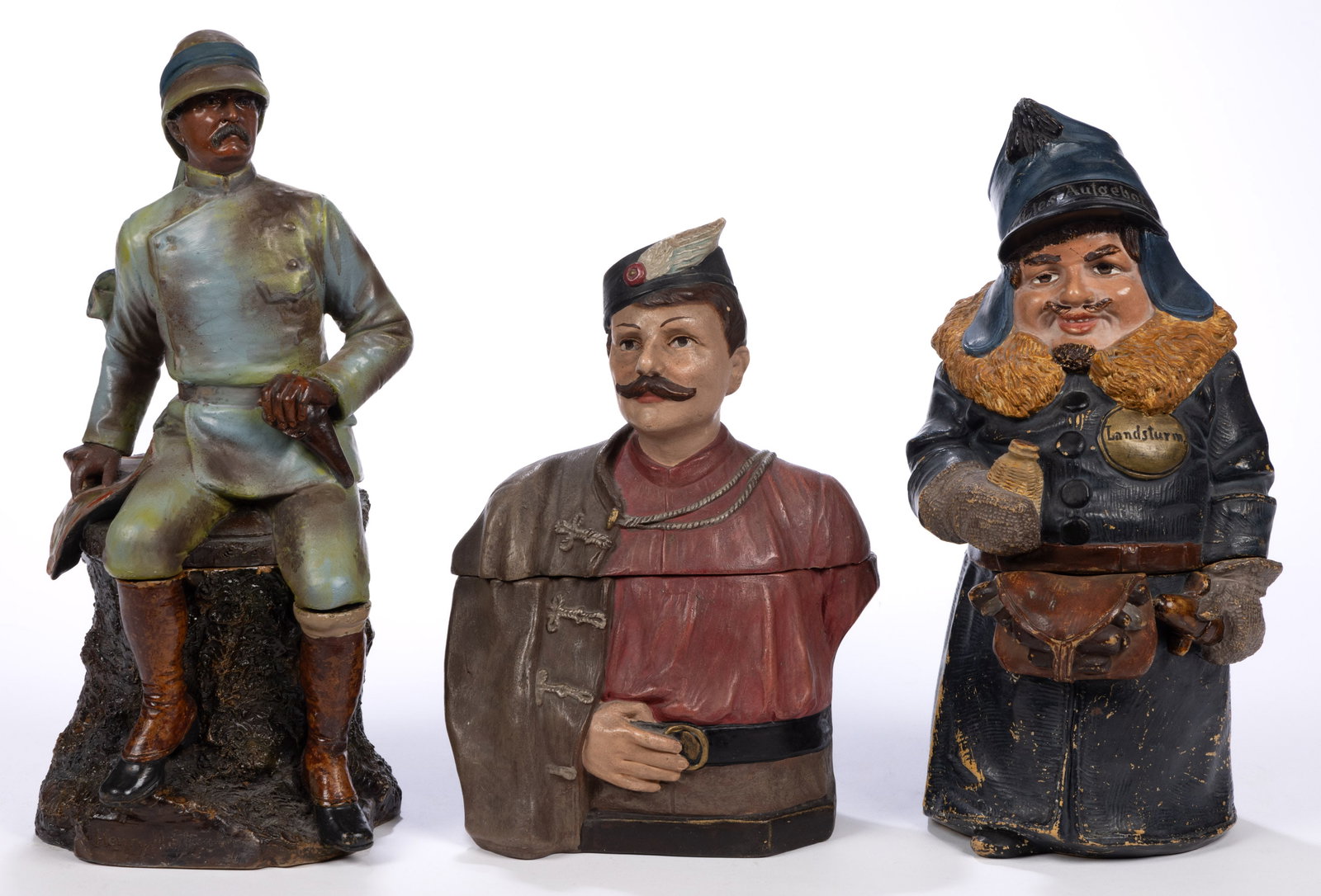 CONTINENTAL CERAMIC MILITARY / UNIFORMED FIGURAL HUMIDORS, LOT OF THREE: CONTINENTAL CERAMIC MILITARY / UNIFORMED FIGURAL HUMIDORS, LOT OF THREE, comprising one example depicting explorer "Henry M. Stanley" in full uniform and sitting on an inscribed stump with a