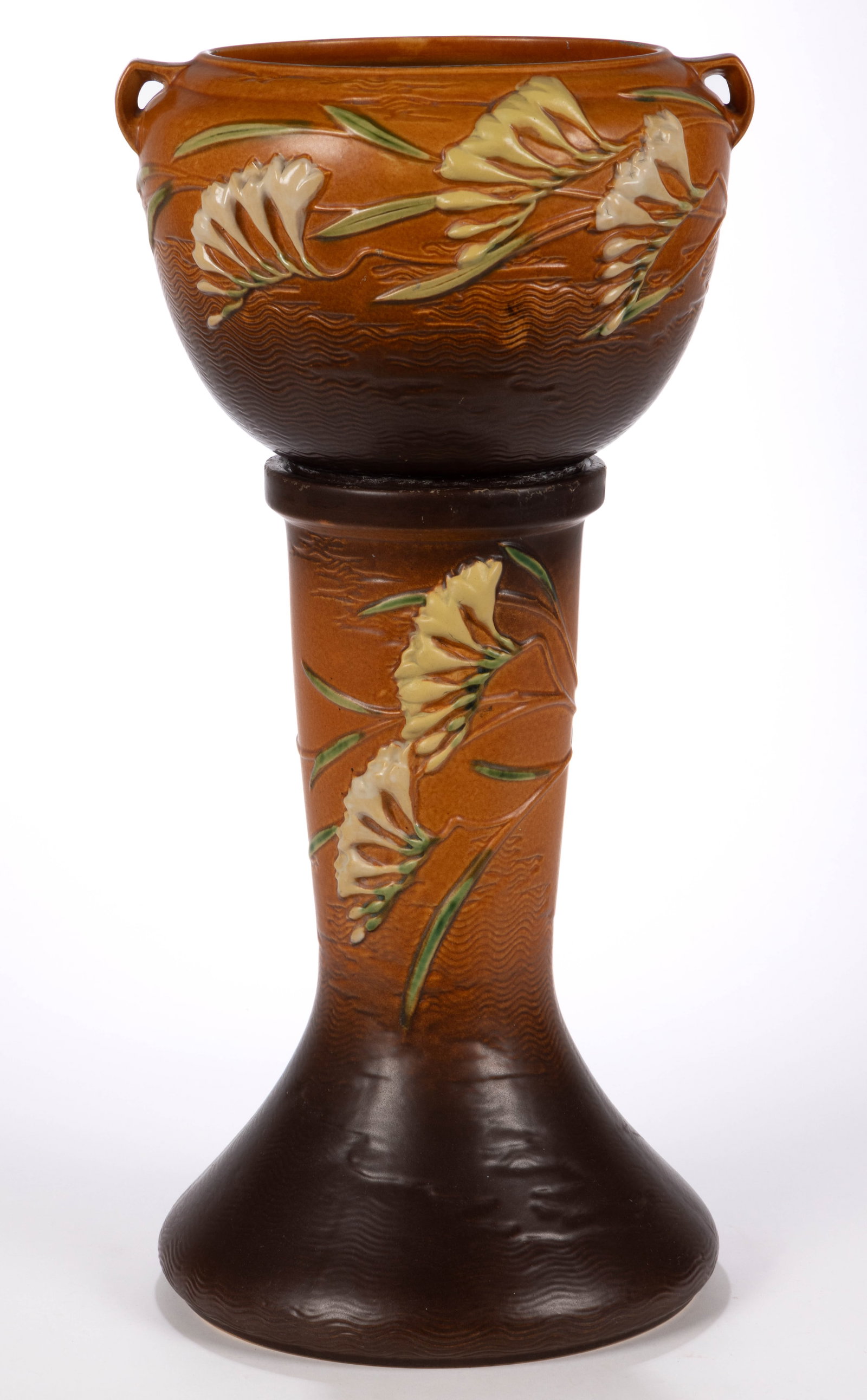 AMERICAN ROSEVILLE ART POTTERY FREESIA JARDINIERE AND PEDESTAL: AMERICAN ROSEVILLE ART POTTERY FREESIA JARDINIERE AND PEDESTAL, each featuring a cluster of trumpet-form ivory and yellow flowers on terra cotta ground with matte glaze, comprising an open-handle