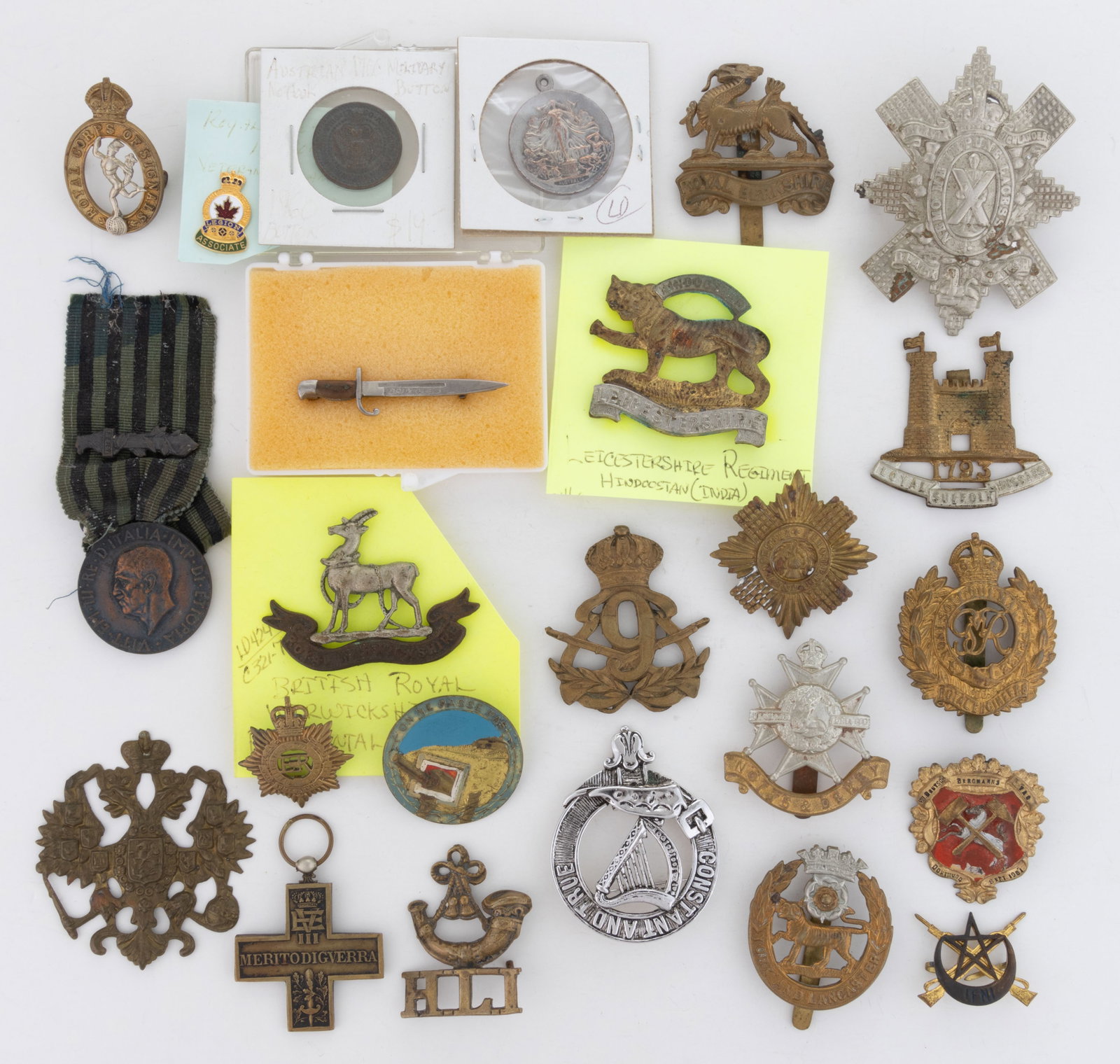 FOREIGN MILITARY INSIGNIA AND RELATED ARTICLES, LOT OF 24: FOREIGN MILITARY INSIGNIA AND RELATED ARTICLES, LOT OF 24, including an Imperial Russian cap badge; a Belgian bayonet-form pin; British regiments; etc. 20th century. 3 1/2" LOA. Provenance: