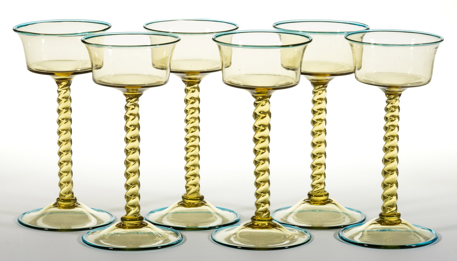 STEUBEN NO. 2991 ART GLASS CHAMPAGNES, LOT OF SIX: STEUBEN NO. 2991 ART GLASS CHAMPAGNES, LOT OF SIX, amber, each having applied Celeste Blue rims to the top rim and edge of the foot, polished pontil mark. Steuben Glass Works. Circa 1925. 8" H.&n