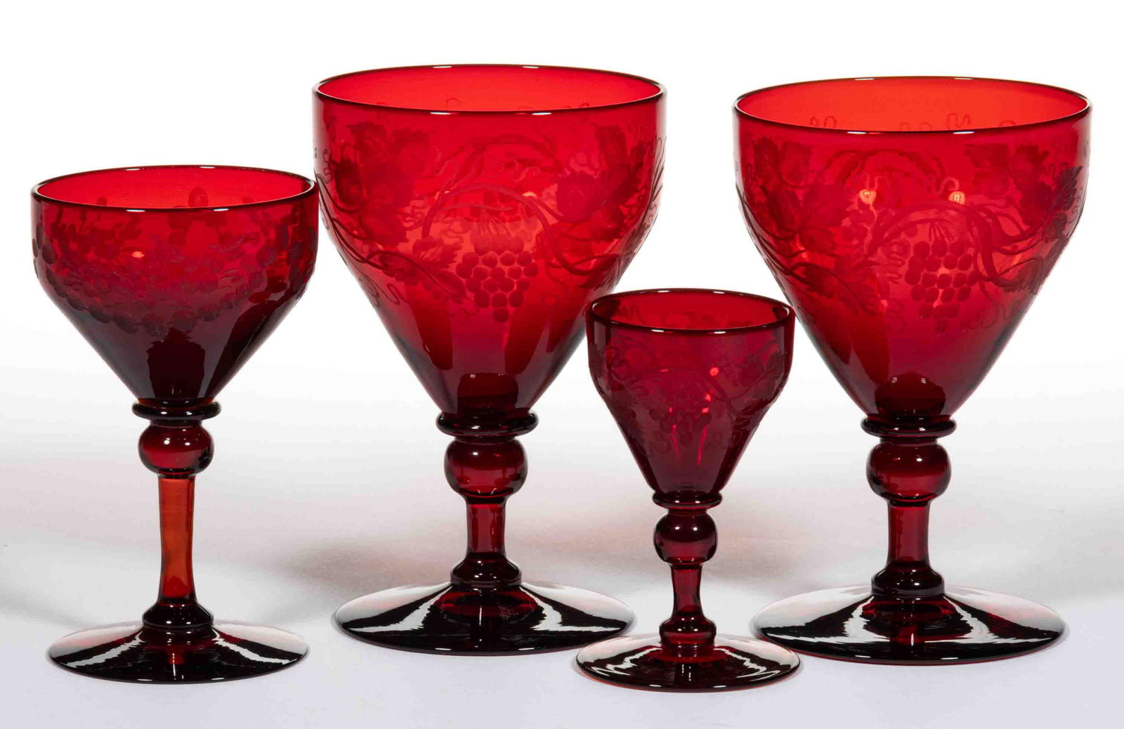 STEUBEN NO. 3140 ENGRAVED ART GLASS DRINKING ARTICLES, LOT OF FOUR: STEUBEN NO. 3140 ENGRAVED ART GLASS DRINKING ARTICLES, LOT OF FOUR, Selenium Red, comprising two goblets with Grapevine decoration, a wine with floral engraving, and a cordial with Grapevine engr