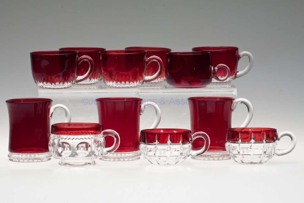 VARIOUS EAPG RUBY-STAINED DRINKING VESSELS, LOT OF: VARIOUS EAPG RUBY-STAINED DRINKING VESSELS, LOT OF 12, colorless, comprising three mugs and nine punch cups. Fourth quarter 19th century. 2" to 3 1/2" H. Provenance: Lillian "Lil" and Walter "Bud" Mar