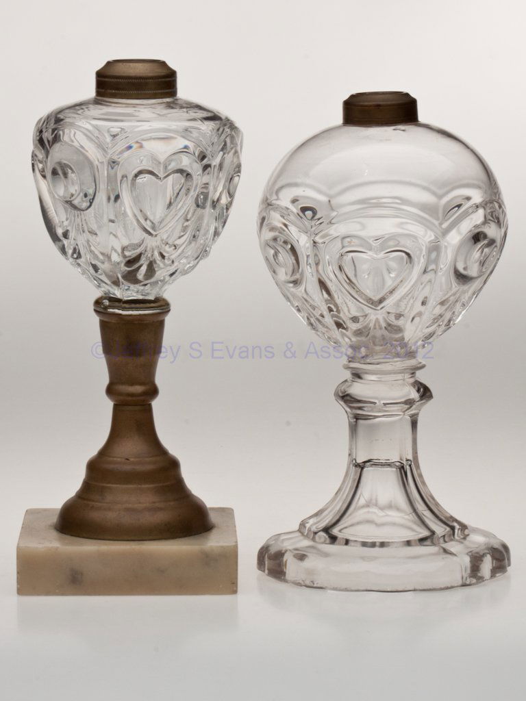 BULL'S EYE, FLEUR-DE-LYS AND HEART STAND LAMPS, LO: BULL'S EYE, FLEUR-DE-LYS AND HEART STAND LAMPS, LOT OF TWO, colorless, comprising one example with octagonal stem, 16-scallop base, brass fine line collar and wafer construction, the other with a bras