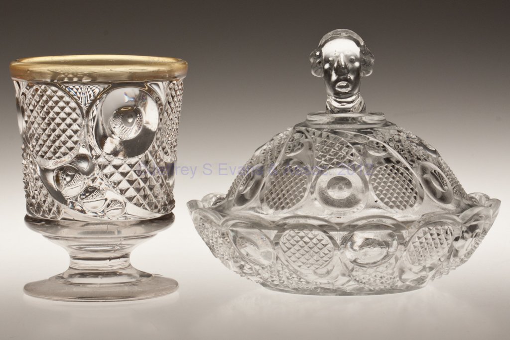 HORN OF PLENTY TABLE ARTICLES, LOT OF TWO: HORN OF PLENTY TABLE ARTICLES, LOT OF TWO, colorless lead glass, comprising a Washington Head covered nappy/butter dish, and a spoon holder/spill with worn gilding over silver-nitrate stain to rim, an
