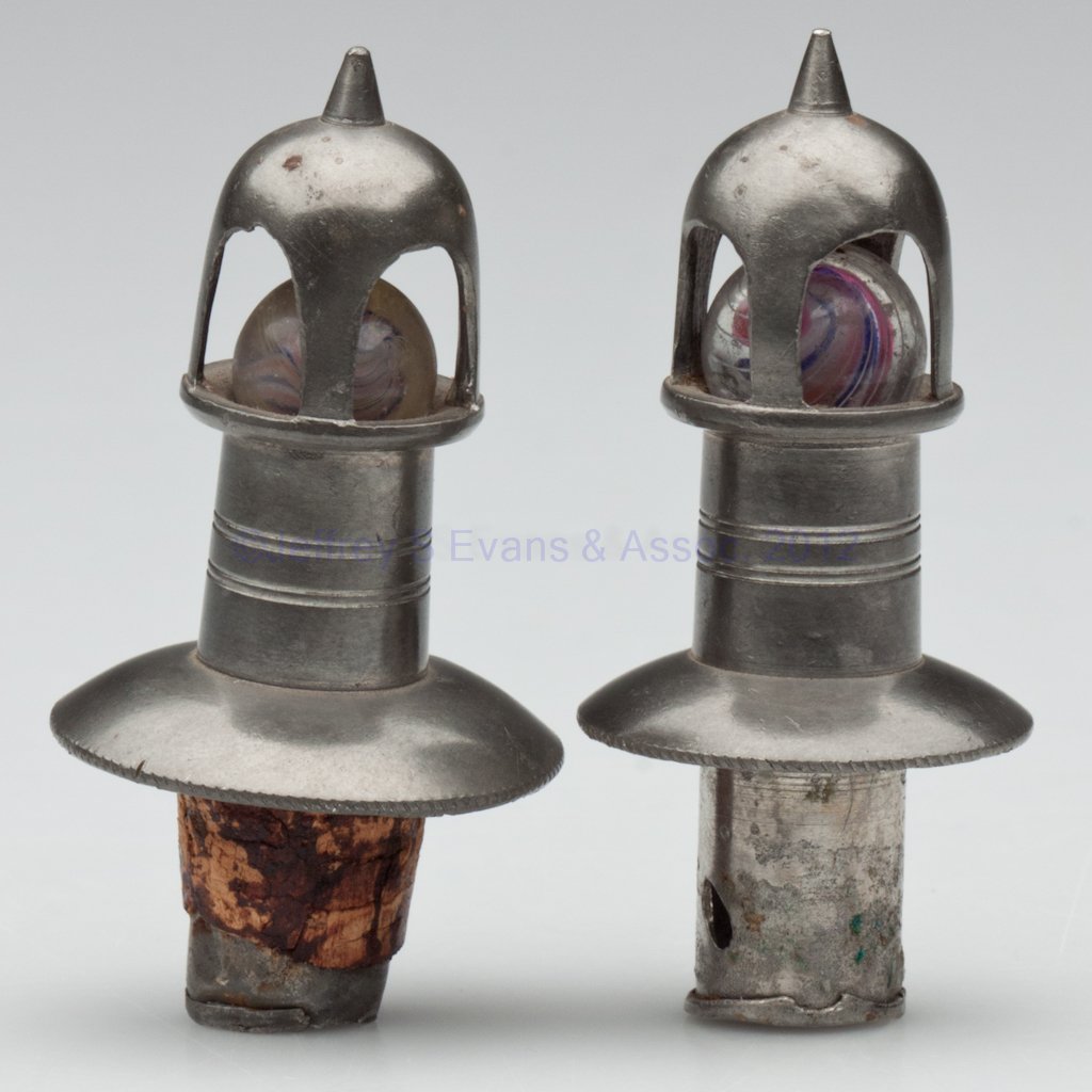 BRITANNIA SLIDE STOPPERS, LOT OF TWO: BRITANNIA SLIDE STOPPERS, LOT OF TWO, each cage style with swirl marble closure and coin-edge flange, no markings. One retains partial cork. Third quarter 19th century. 2 3/4" HOA. Provenance: From a 