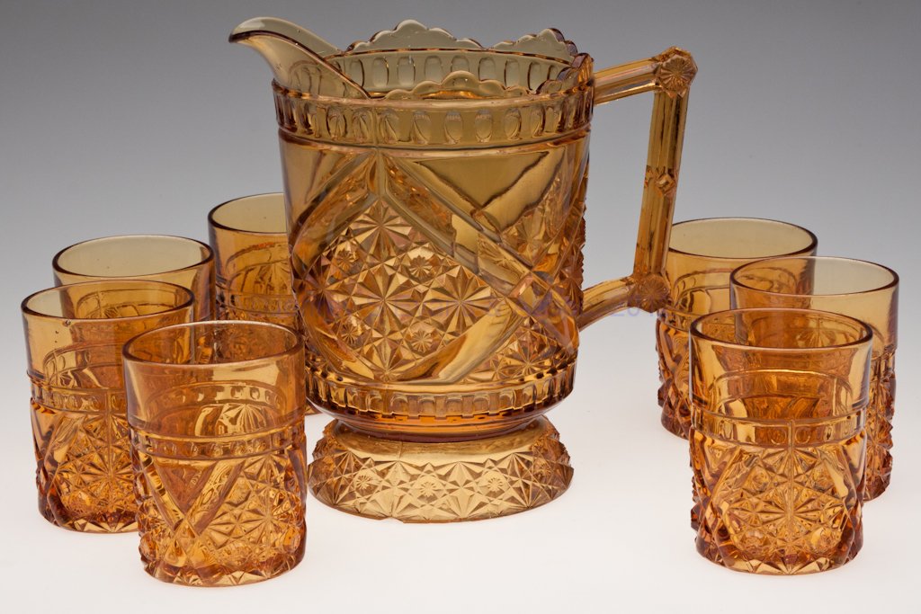 DAISY AND BUTTON WITH CROSS BARS EIGHT-PIECE WATER: DAISY AND BUTTON WITH CROSS BARS EIGHT-PIECE WATER SET, deep amber, comprising a half-gallon pitcher and seven tumblers. Fourth quarter 19th century. Tumblers 3 3/8" H, pitcher 8" H. Provenance: Lilli