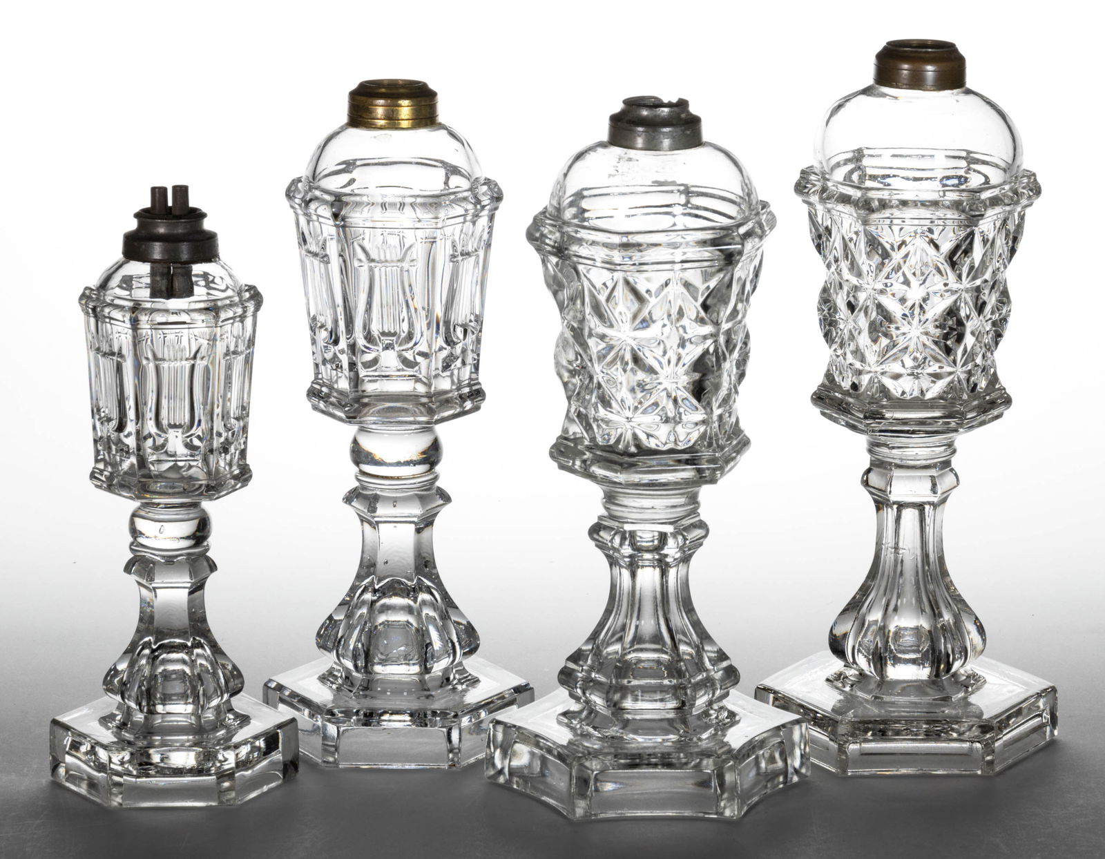 FLINT EAPG WHALE OIL / FLUID STAND LAMPS, LOT OF FOUR: FLINT EAPG WHALE OIL / FLUID STAND LAMPS, LOT OF FOUR, colorless lead glass, comprising two Lyre and two Sandwich Star examples, each having a pewter or brass collar. Shortest Lyre fitted with a perio