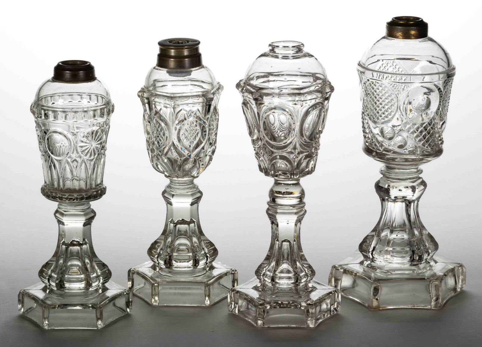 FLINT EAPG WHALE OIL / FLUID STAND LAMPS, LOT OF FOUR: FLINT EAPG WHALE OIL / FLUID STAND LAMPS, LOT OF FOUR, colorless lead glass, including a Moorish, a Horn of Plenty, and an Excelsior, three having a period brass collar, Excelsior lacking collar. One 