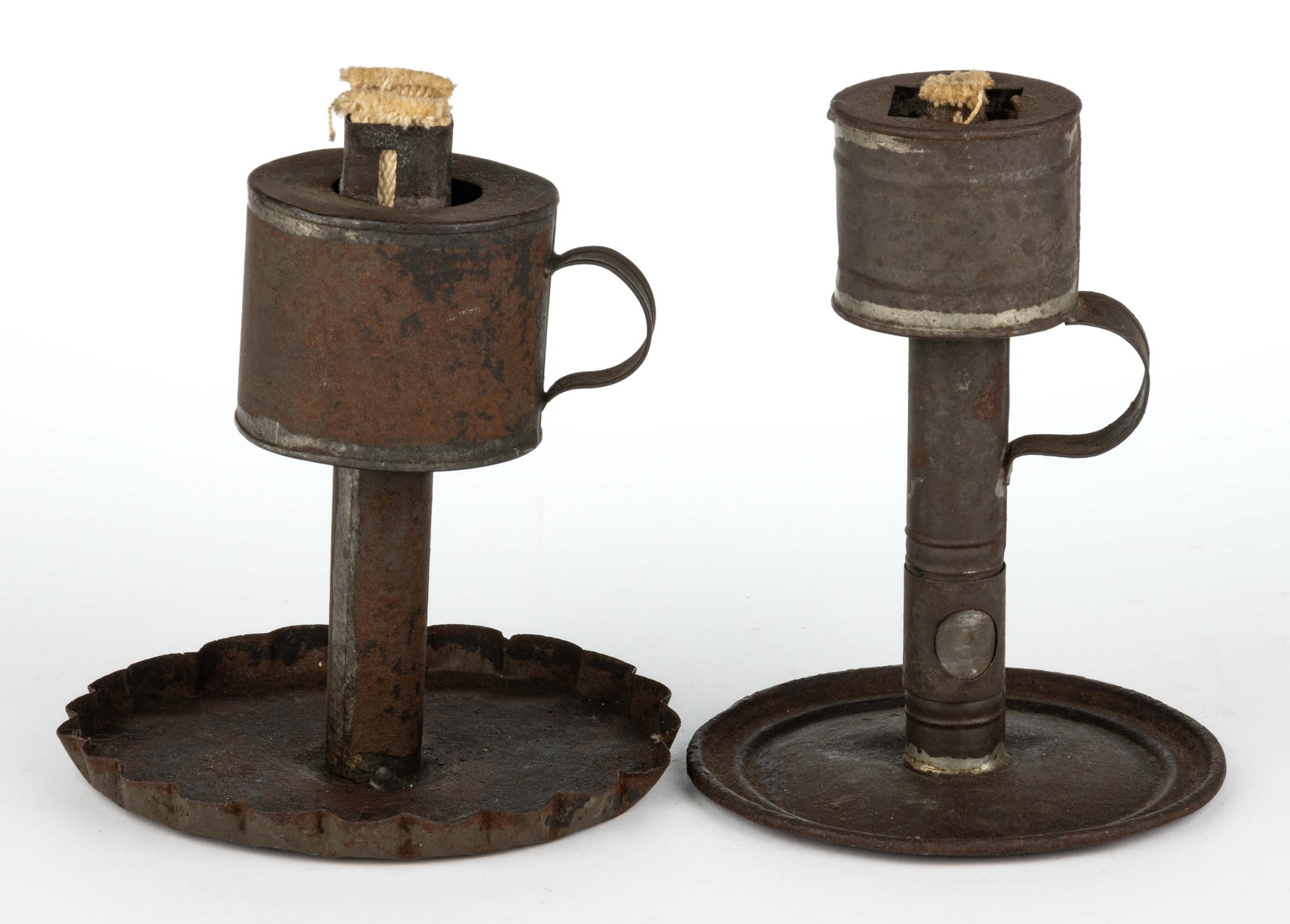 ASSORTED SHEET-IRON GREASE / LARD / OIL FOOTED FINGER LAMPS, LOT OF TWO: ASSORTED SHEET-IRON GREASE / LARD / OIL FOOTED FINGER LAMPS, LOT OF TWO, each with a cylinder-form font and a saucer foot, one example with a crimped rim and remaining with a stamped ring, one st