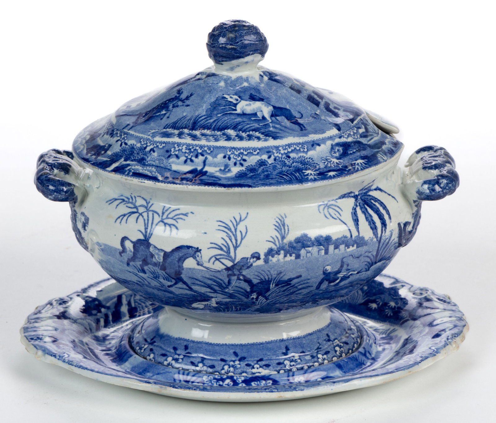 STAFFORDSHIRE TRANSFER-PRINTED INDIAN SPORTING SERIES CERAMIC SAUCE TUREEN AND UNDERTRAY: STAFFORDSHIRE TRANSFER-PRINTED INDIAN SPORTING SERIES CERAMIC SAUCE TUREEN AND UNDERTRAY, each of ovoid form with borders depicting assorted animals, comprising a tureen with applied double-loop 