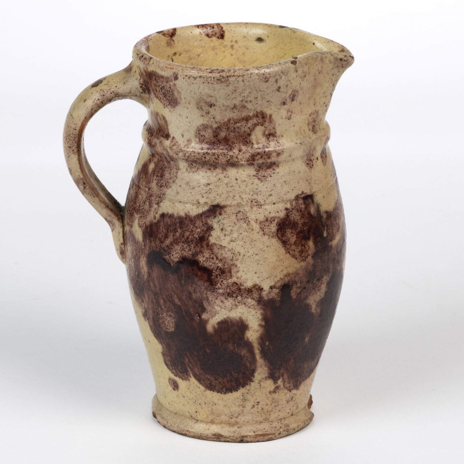 STRASBURG, SHENANDOAH VALLEY OF VIRGINIA POLYCHROME-DECORATED EARTHENWARE / REDWARE CREAM PITCHER: STRASBURG, SHENANDOAH VALLEY OF VIRGINIA POLYCHROME-DECORATED EARTHENWARE / REDWARE CREAM PITCHER, lead- and manganese-glazed over a slip wash, ovoid form with flared mouth, beaded neck, sin