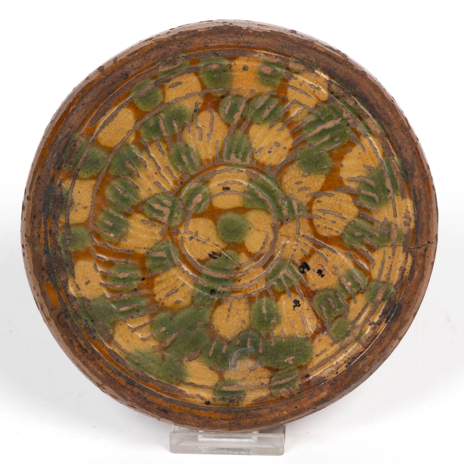 MID-ATLANTIC POLYCHROME-DECORATED EARTHENWARE / REDWARE TRIVET: MID-ATLANTIC POLYCHROME-DECORATED EARTHENWARE / REDWARE TRIVET, lead-, copper-, and yellow-glazed, low circular form with impressed radiating line decoration to top and eight applied circular bud feet