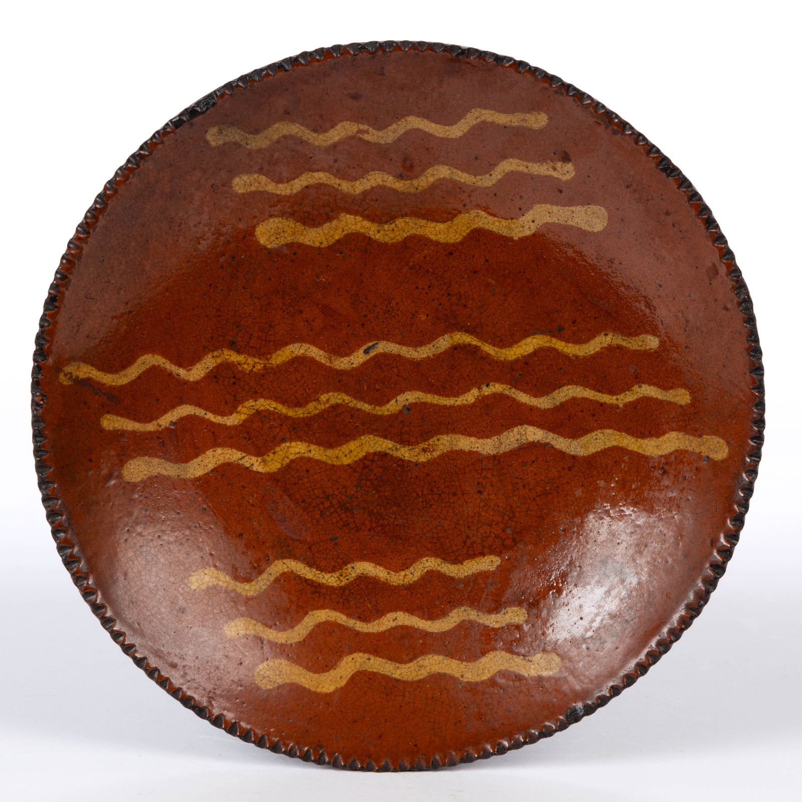 PENNSYLVANIA DECORATED EARTHENWARE / REDWARE DISH / PLATE: PENNSYLVANIA DECORATED EARTHENWARE / REDWARE DISH / PLATE, single lead-glazed, coggled rim. Yellow slip-trailed triple wavy line decorations in three bands. First half 19th century. 8" D. Pr