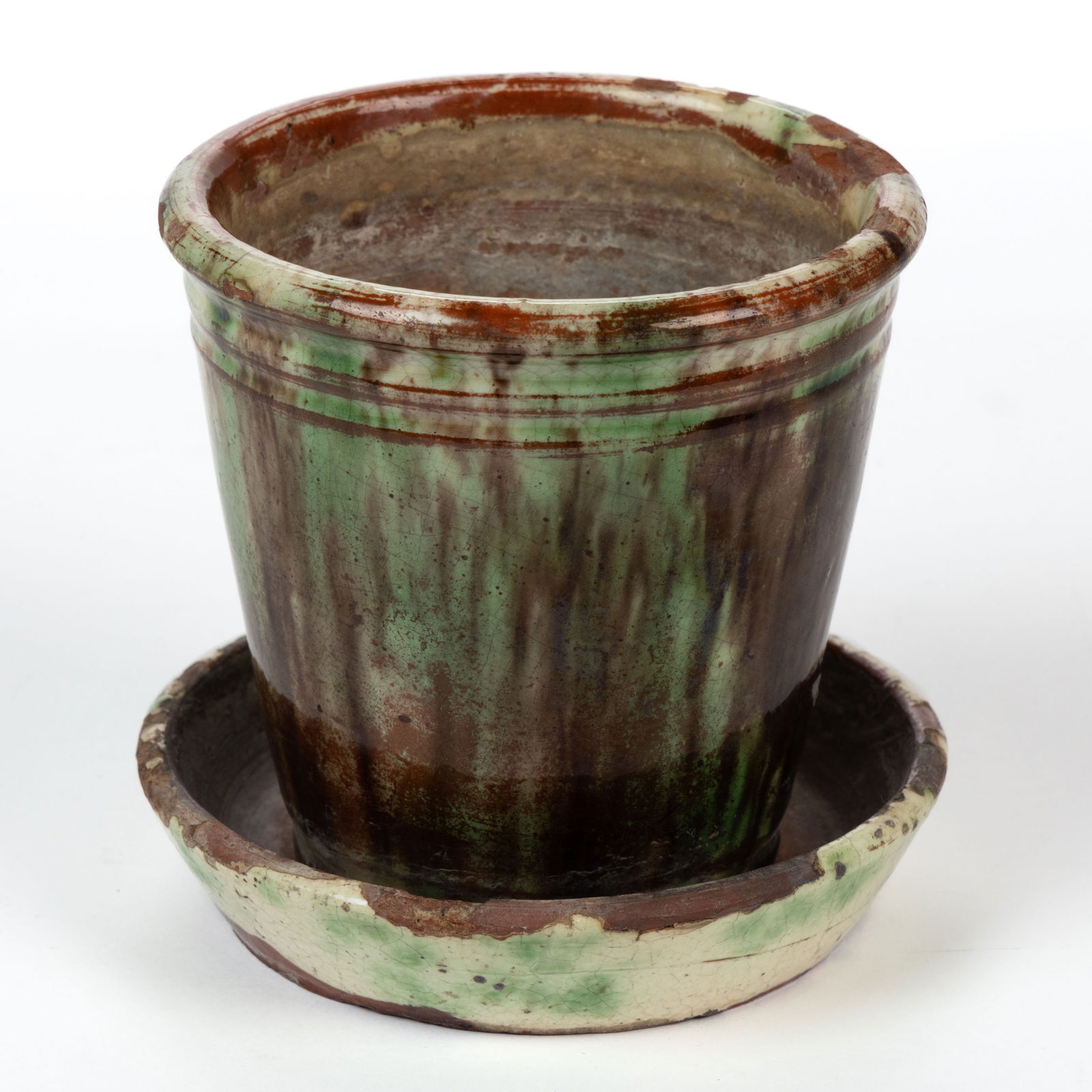 PENNSYLVANIA POLYCHROME-DECORATED EARTHENWARE / REDWARE FLOWER POT AND SAUCER: PENNSYLVANIA POLYCHROME-DECORATED EARTHENWARE / REDWARE FLOWER POT AND SAUCER, lead-, copper-, and manganese-glaze over a slip wash, conical form with rounded rim and double neck rings, punched d