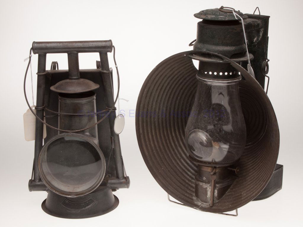 VARIOUS SHEET IRON TUBULAR LANTERNS, LOT OF TWO: VARIOUS SHEET IRON TUBULAR LANTERNS, LOT OF TWO, each with bail handle, comprising a C. T. Ham Manuf. Co. "No. 20" cold blast example, painted green and with wall mount, colorless globe with 2 1/4" bu