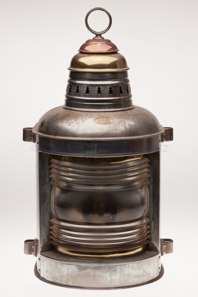 PERKINS "PERKO" BRASS AND SHEET IRON MASTHEAD MARI: PERKINS "PERKO" BRASS AND SHEET IRON MASTHEAD MARINE LANTERN, iron ring handle, flat back, cap with copper, top and bottom each with two mounting lugs, maker's plate marked "PERKINS MARINE LAMP & HDWE
