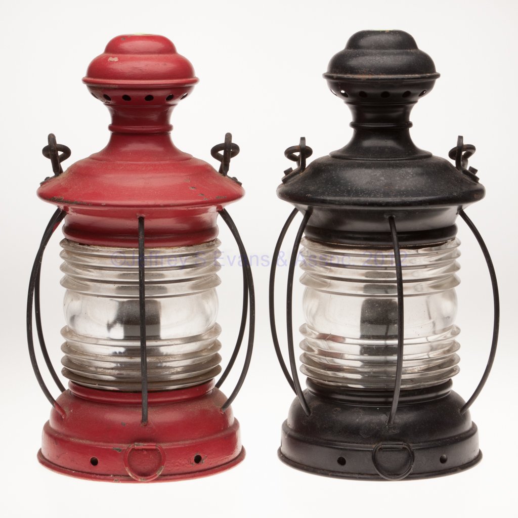 PAINTED SHEET IRON MARINE LANTERNS, LOT OF TWO: PAINTED SHEET IRON MARINE LANTERNS, LOT OF TWO, one example painted red and other black, bail handles, bases with two tie-down rings, colorless 360 degree fresnel lens with vertical wire guards, one e