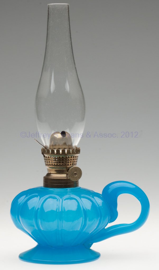 COLORED GLASS FOOTED FINGER LAMP: COLORED GLASS FOOTED FINGER LAMP, starch blue, loop patterned font, applied handle, No. 1 fine line collar. Fitted with a period Holmes, Booth & Haydens No. 0 lip burner, thumbwheel marked "HOLMES BOO