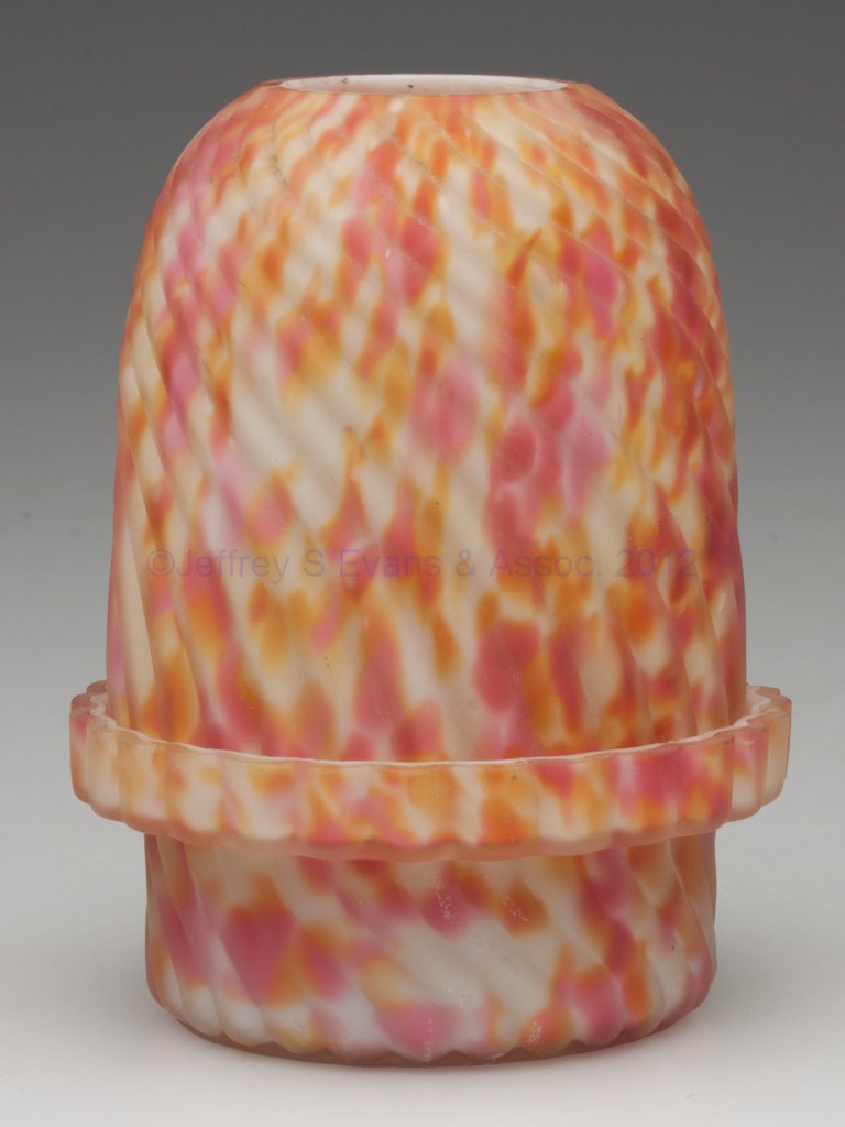 SWIRLED RIB FAIRY LAMP: SWIRLED RIB FAIRY LAMP, satin cased rainbow spatter, colorless candle cup embossed with Clarke's US Patent number and 1886 date. Fourth quarter 19th century. 4 1/2" H, 3 5/8" D base. Literature: Paral